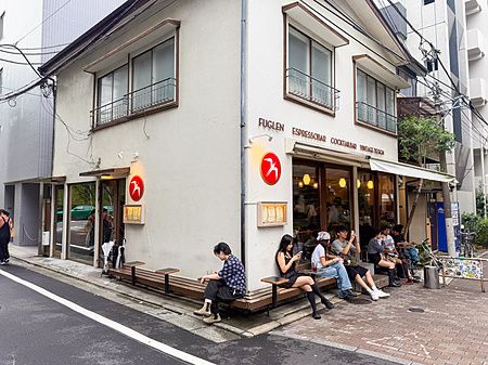 Esterno della caffetteria Fuglen vicino alla stazione Yoyogi-Hachiman a Tokyo con persone sedute sulle panche.