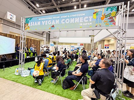Una folla di persone sedute su sedie pieghevoli segue un seminario durante la Good Life Fair di Tokyo.