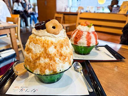 Due ciotole di kakigori con miso d'orzo e pesce servite su vassoi neri all'interno del locale Kanna a Tokyo.