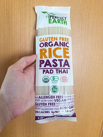 Mano che tiene confezione di pasta di riso pad thai senza glutine in Giappone.