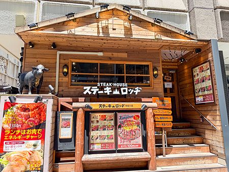 La facciata in legno del Ristorante Steak Lodge (Udagawacho), Shibuya, Tokyo, con insegne di menu e una statua di un toro.