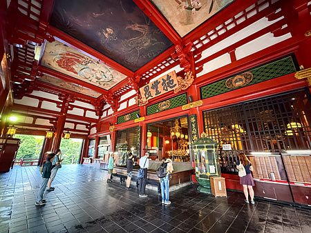Interno del tempio Senso-ji ad Asakusa con persone e decorazioni tradizionali.