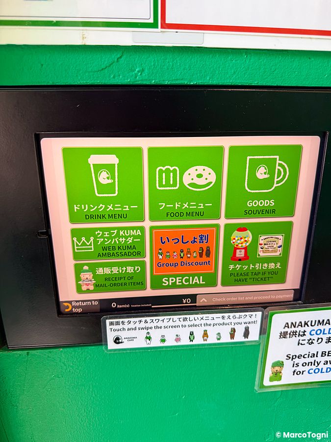 Schermo digitale verde di ordinazione presso l'Anakuma Cafe ad Harajuku con icone per menu, cibo e gadget.