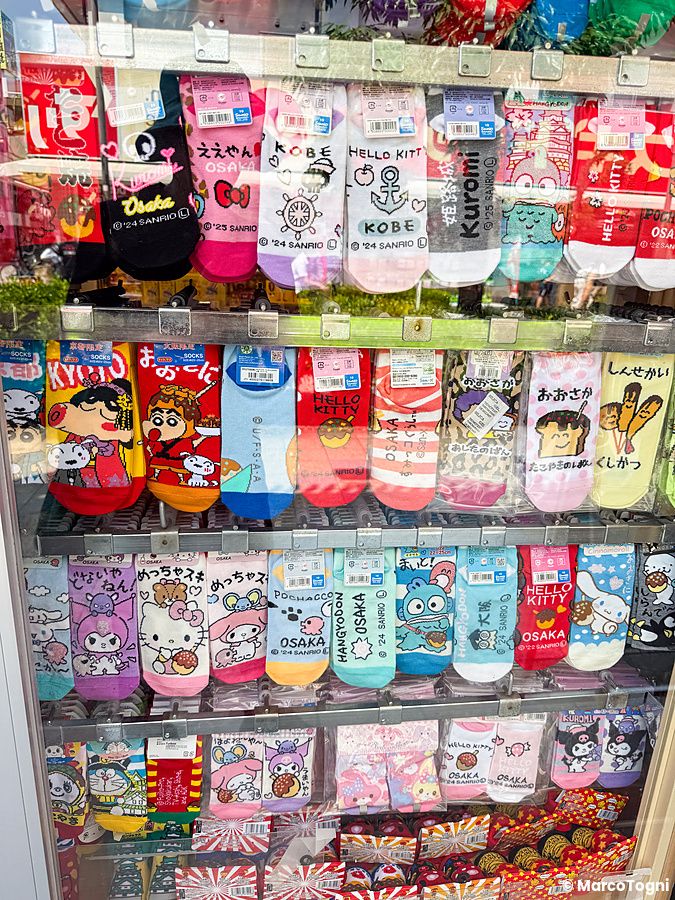 Espositore di calzini souvenir ad Osaka con vari personaggi Sanrio e icone tematiche giapponesi in vendita.