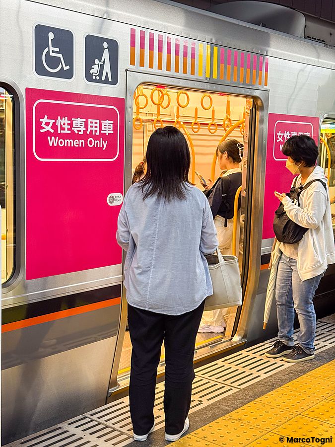 Persone in attesa di salire su una carrozza per sole donne su un treno ad Osaka presso una stazione ferroviaria.