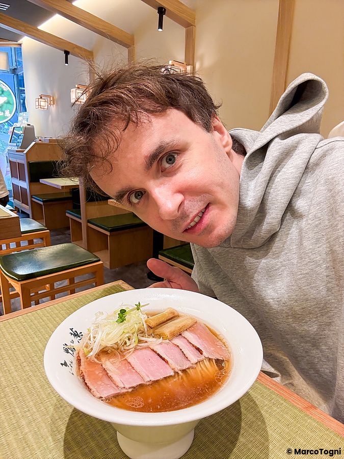 Marco Togni posa con una ciotola di ramen con carne d'anatra all'interno del ristorante Ramen Kamo to Negi.
