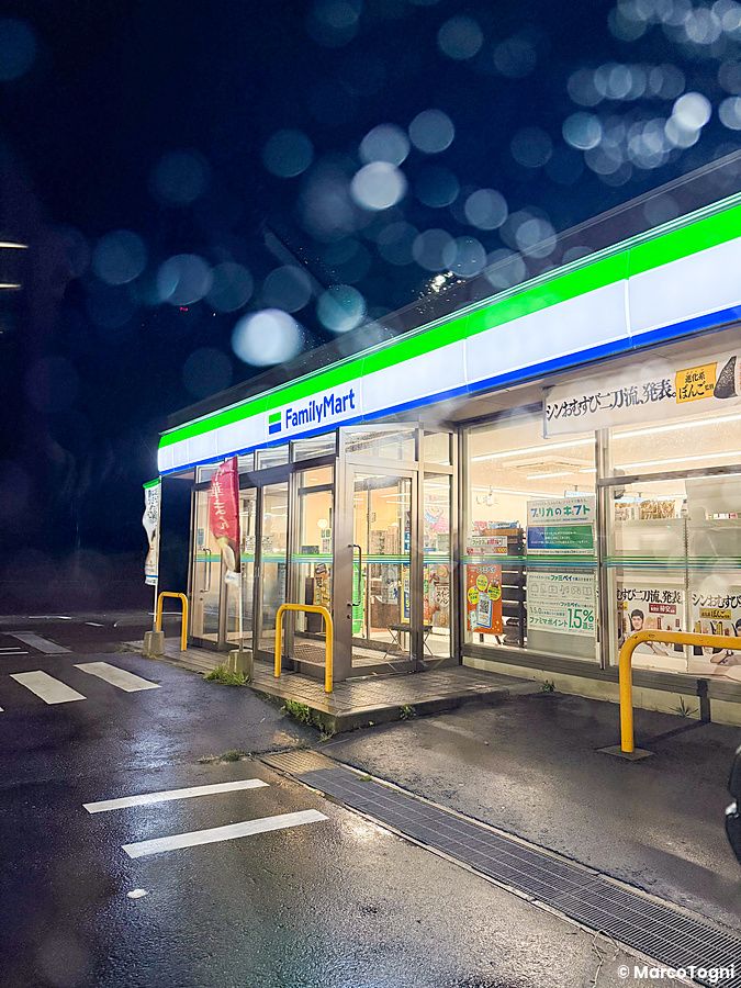 Family Mart in Giappone illuminato di notte con strada bagnata.