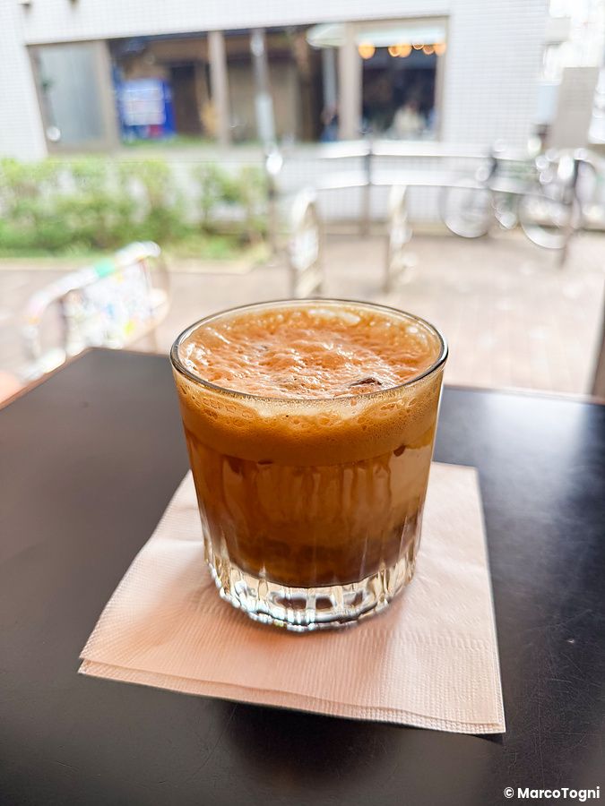 Un bicchiere di caffè espresso con schiuma su un tovagliolo bianco appoggiato a un tavolo di Fuglen a Tokyo.