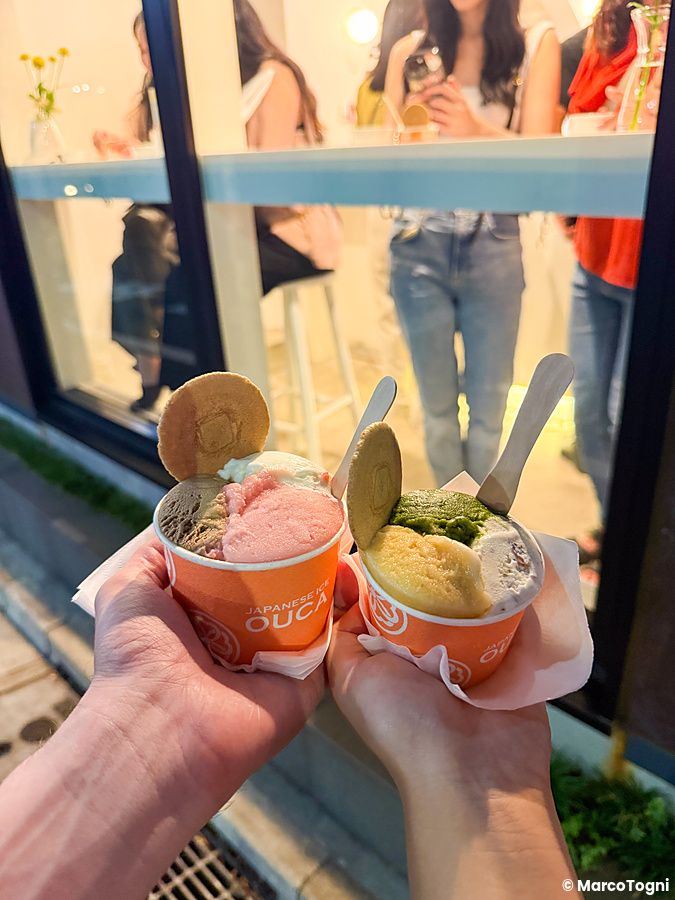 Due coppette di gelato con logo Ouca tenute in mano davanti alla vetrina della gelateria giapponese Ouca a Ebisu.