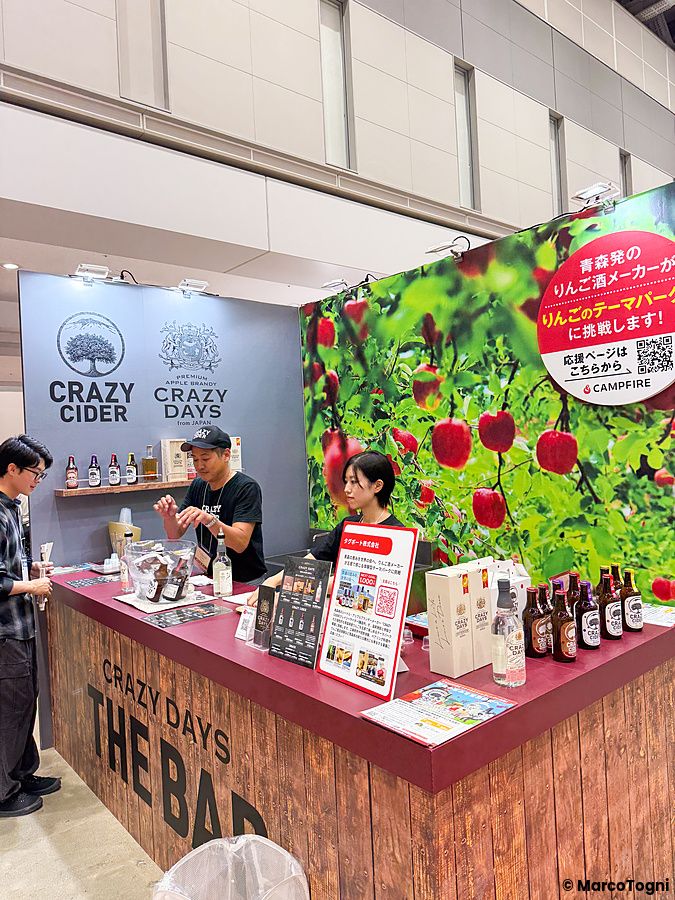 Uno stand di CRAZY DAYS alla Good Life Fair di Tokyo con due persone che servono bottiglie di sidro di mele.