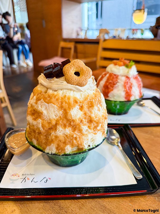 Due ciotole di kakigori, con miso d'orzo e con pesce, servite su vassoi neri presso il ristorante Kanna a Setagaya.
