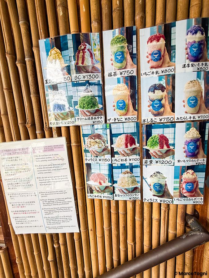 Menù illustrato con foto di dolci kakigori e regolamento del locale Kanna esposto su una parete di bambù a Tokyo.