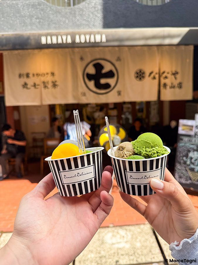 Due persone tengono in mano coppette di gelato di fronte all'insegna del negozio Nanaya ad Aoyama, Tokyo.