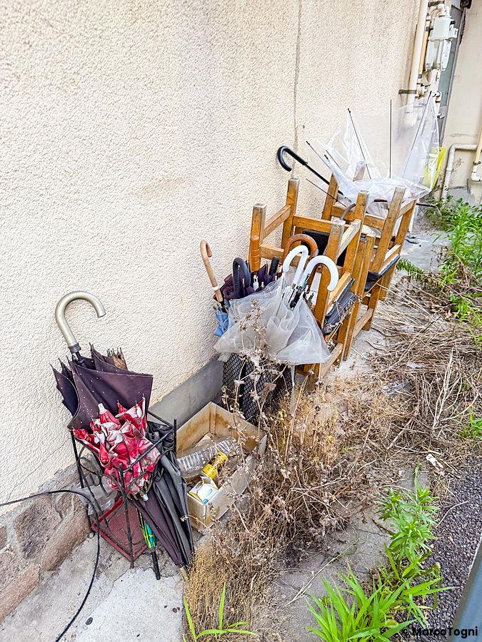 Una collezione di ombrelli portaombrelli in Giappone poggiata contro una parete esterna in un'area urbana.