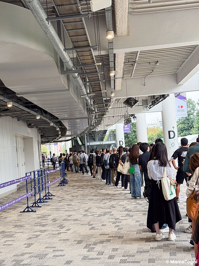 Persone in fila all'ingresso dello Stadio Nazionale Giapponese a Tokyo.