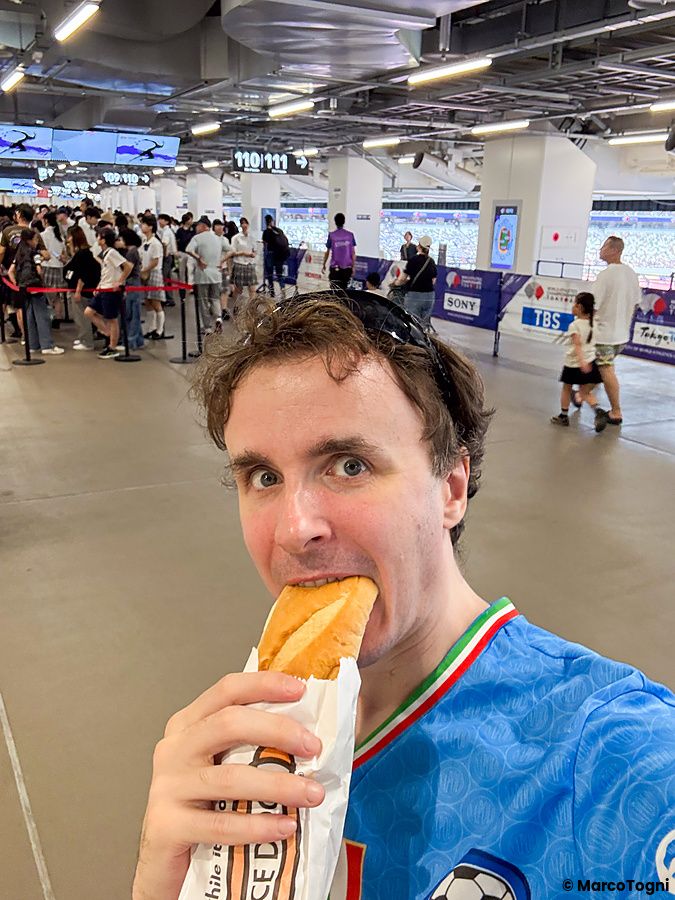 Marco Togni si scatta un selfie mentre mangia un panino all'interno dello Stadio Nazionale Giapponese a Tokyo.