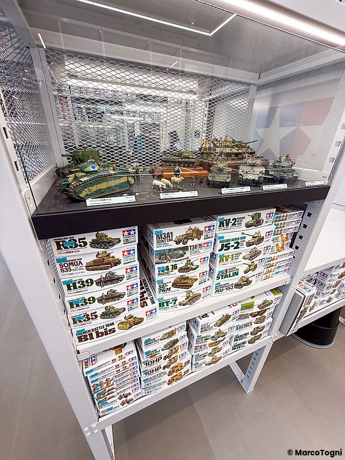 Scaffali pieni di scatole di modellini di carri armati Tamiya e un diorama in una teca al Tamiya PlaModel Factory a Tokyo.