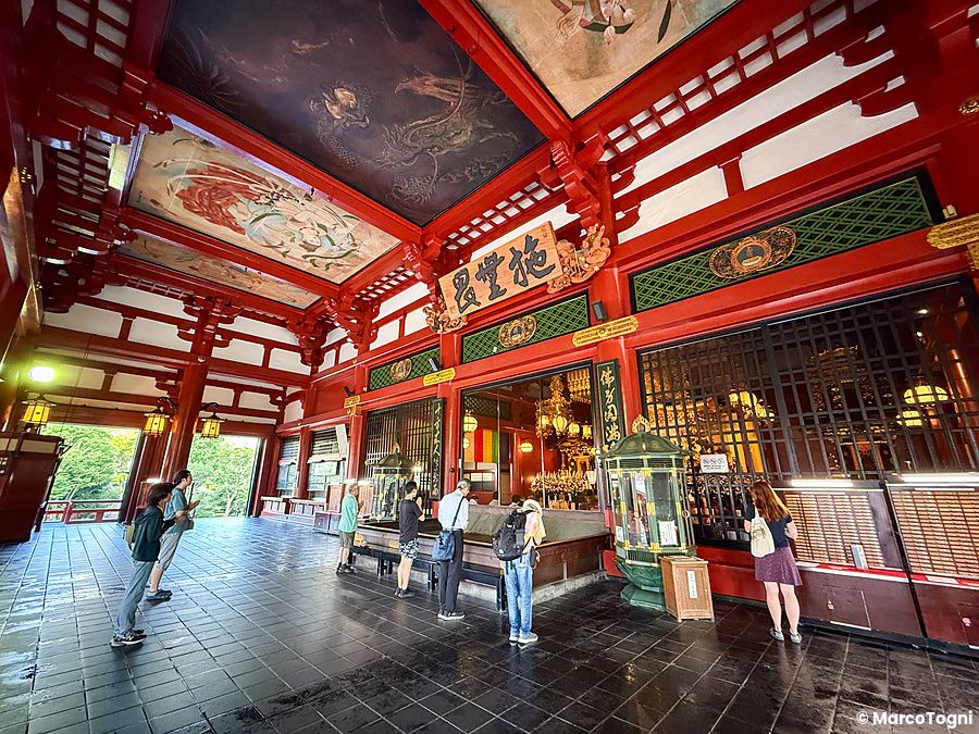 Interno del tempio Senso-ji ad Asakusa con persone e decorazioni tradizionali.
