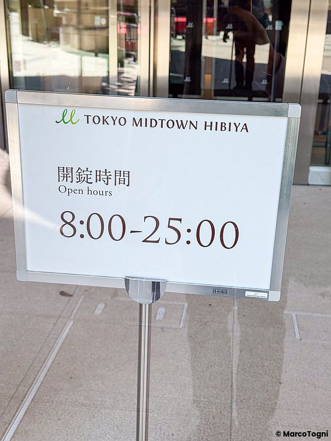 Cartello informativo con orario fino alle ore 25 davanti a Tokyo Midtown Hibiya in Giappone.