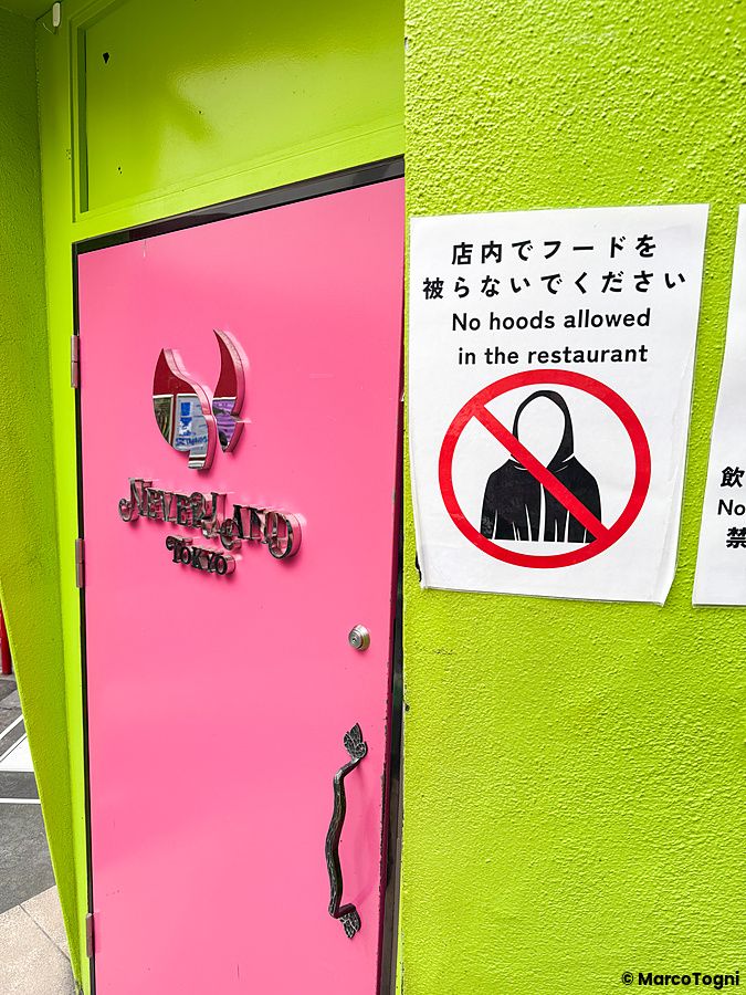 Porta rosa e cartello di divieto di cappucci in Giappone.