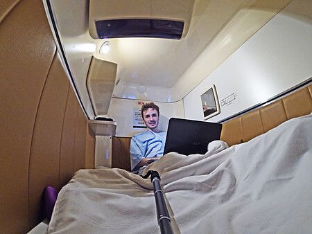Marco Togni usa un portatile all'interno di un capsule hotel a Tokyo.