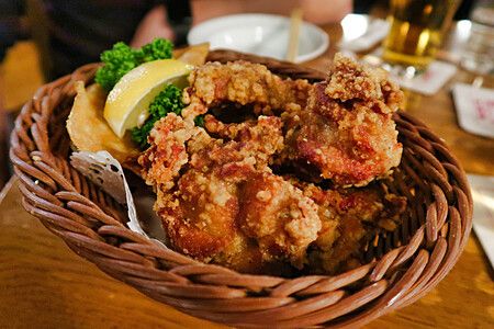 Pollo fritto in stile karaage servito in un cestino di vimini con spicchio di limone presso Ginza Lion a Tokyo.