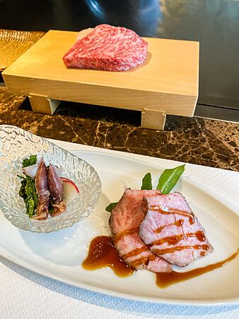 Piatti con manzo di Kobe e calamari al Kobe Beef Ishida di Ginza, con carne cruda su un tagliere di legno.