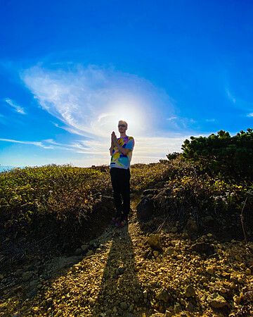 Persona su un sentiero roccioso con cielo blu.
