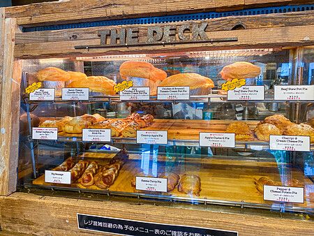 Una vetrina in legno e vetro con una selezione di torte salate e dolci presso The Deck Coffee & Pie a Tokyo.