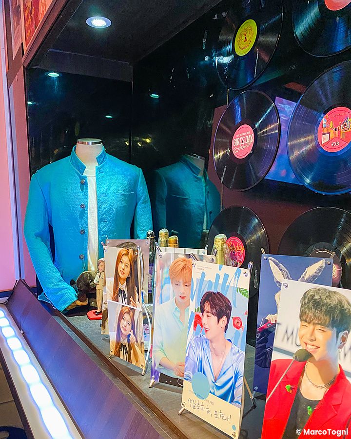 Interno del Cafe ON a Shin-Okubo, Tokyo, con foto di idol K-pop, un manichino in giacca turchese e dischi in vinile.