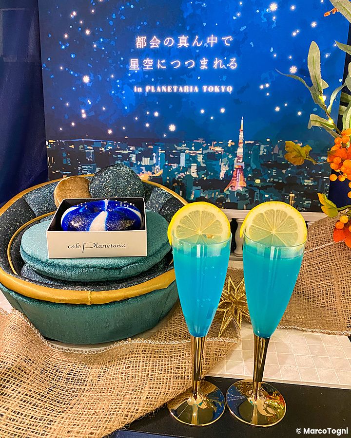 Un donut blu e bianco con due cocktail azzurri decorati con limone su un vassoio al Cafe Planetaria di Tokyo.