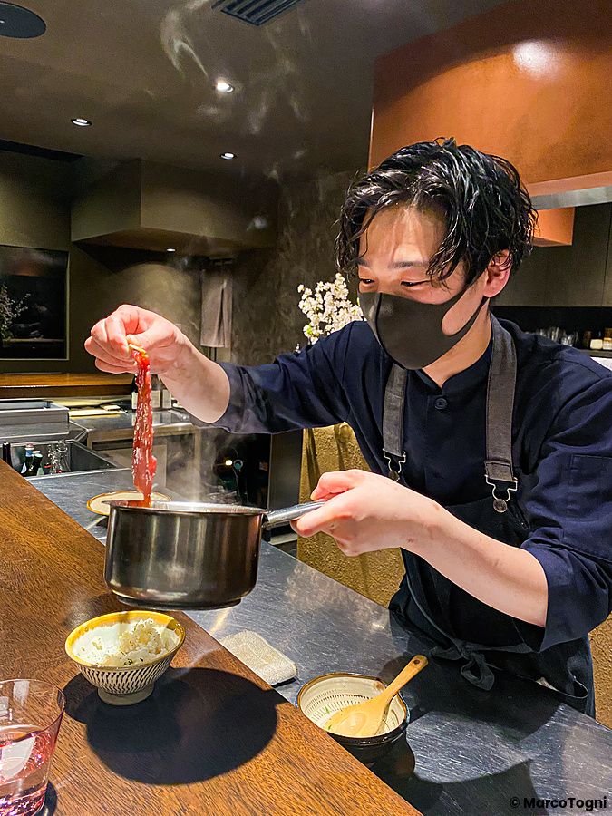 Uno chef con mascherina prepara del carpaccio di wagyu presso il ristorante Denkushiflori a Tokyo.