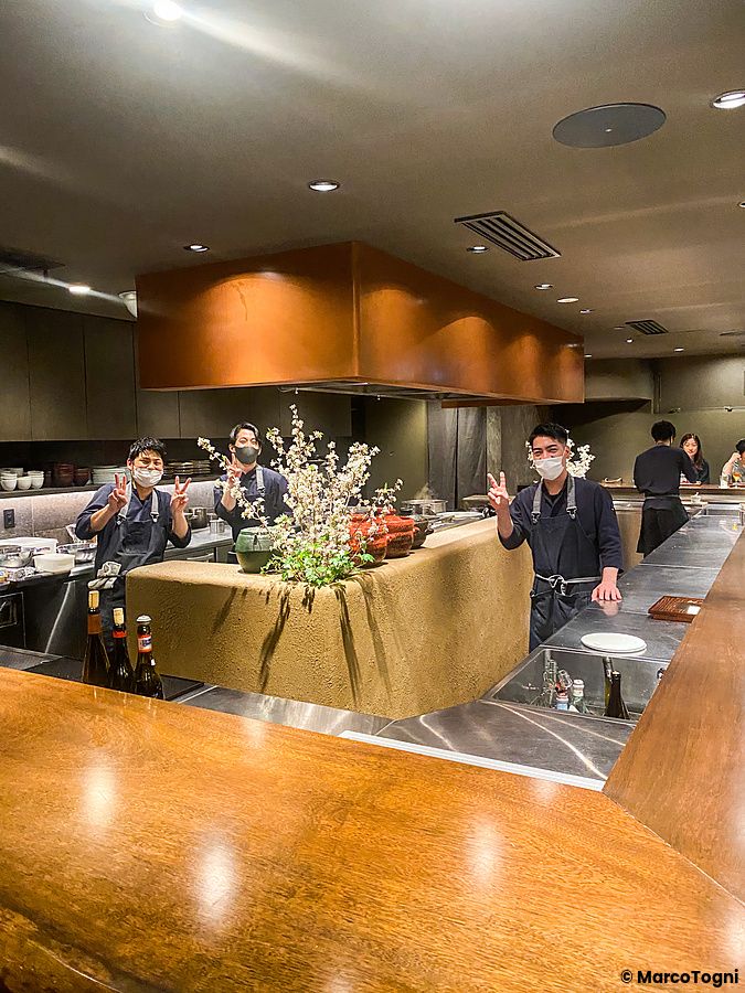 Tre persone in divisa da chef posano dietro il bancone di Denkushiflori a Tokyo.