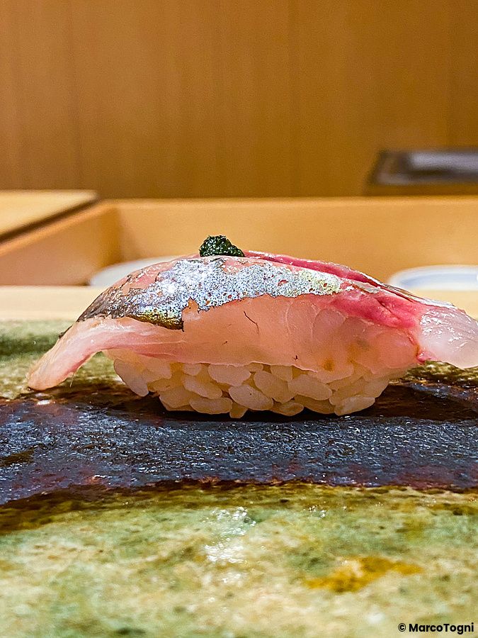 Un Aji nigiri servito su un piatto di ceramica scura presso il ristorante Ginza Iwa nel quartiere di Ginza a Tokyo.