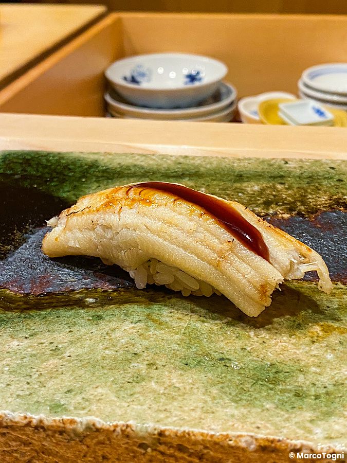 Nigiri di anago con salsa servito su un piatto in ceramica al ristorante Ginza Iwa a Tokyo.