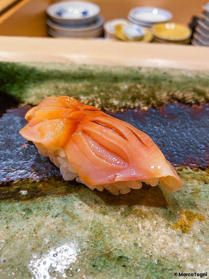 Un Nigiri di ricciola posizionato su un piatto in ceramica ruvida all'interno del ristorante Ginza Iwa a Tokyo.