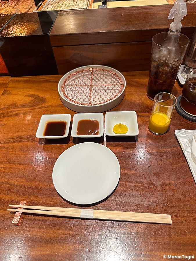 Postazione apparecchiata con salse e griglia per tonkatsu presso il Ginza Katsukami a Tokyo.