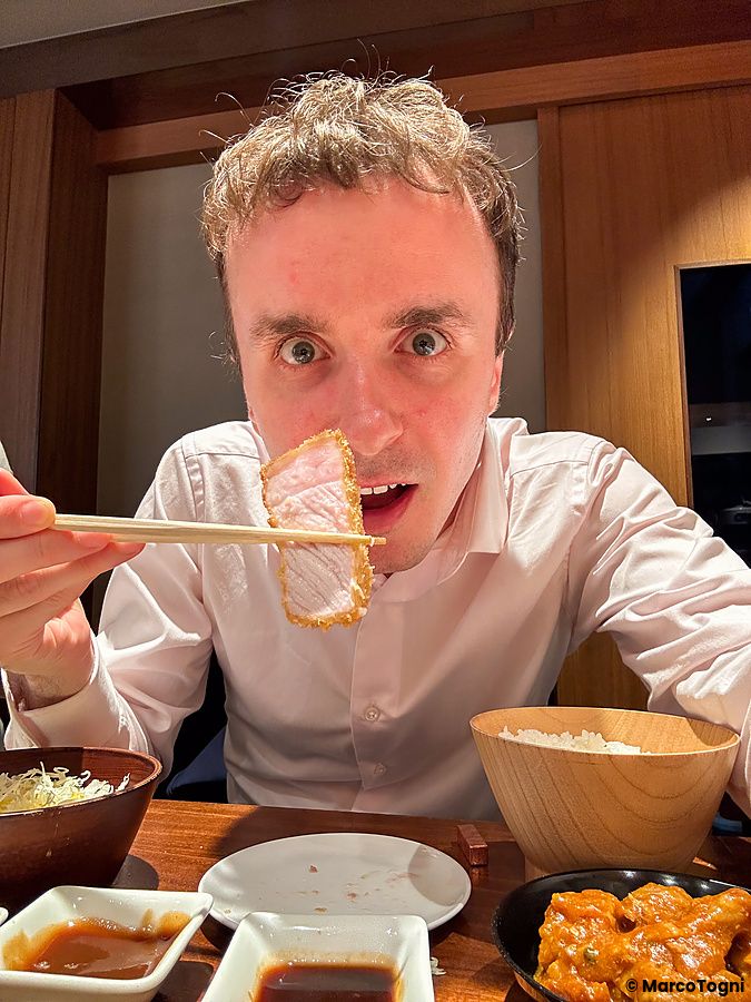 Marco Togni tiene una fetta di tonkatsu con le bacchette all'interno del ristorante Ginza Katsukami a Tokyo.