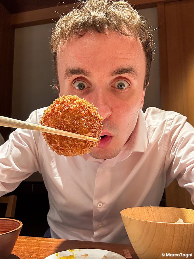 Marco Togni tiene una frittura di maiale con le bacchette all'interno del ristorante Ginza Katsukami a Tokyo.