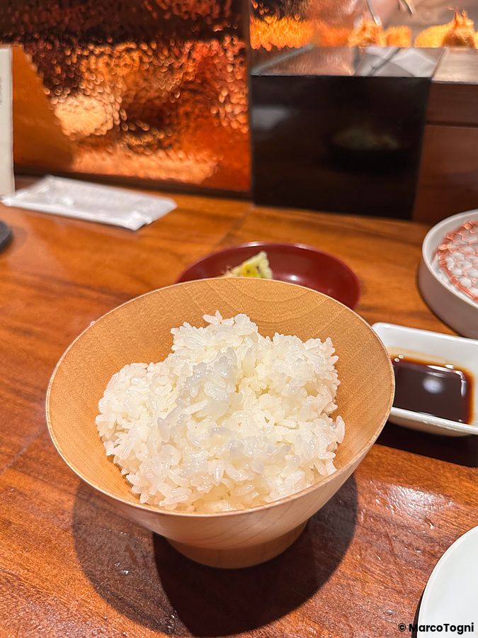 Una ciotola di riso bianco in legno su un bancone di un ristorante al Ginza Katsukami.
