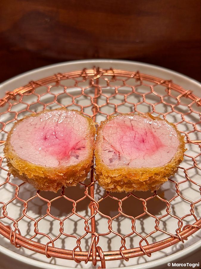Due fette di filetto di maiale fritto nel Ginza Katsukami a Tokyo, adagiate su una griglia circolare.