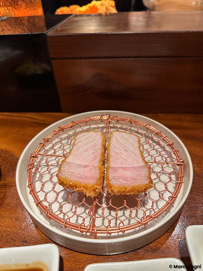 Due fette di tonkatsu fritto con interno rosato su una griglia al ristorante Ginza Katsukami a Tokyo.