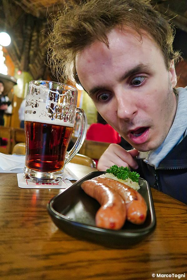 Marco Togni guarda con stupore un piatto di salsicce vicino a un boccale di birra al Ginza Lion.