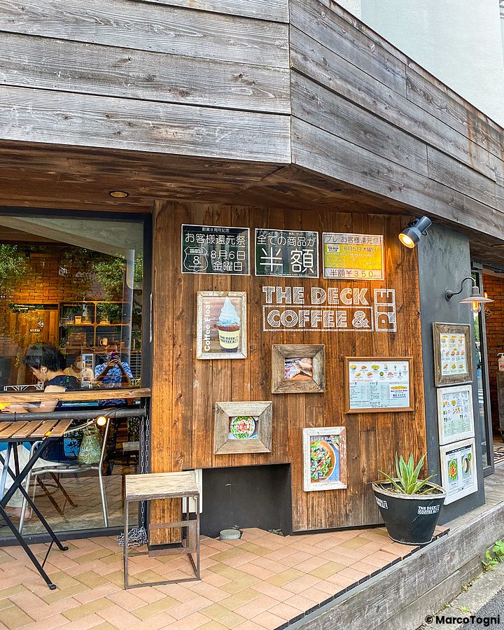 L'ingresso in legno del locale The Deck Coffee & Pie a Tokyo con menu incorniciati sulla parete e una persona dentro.