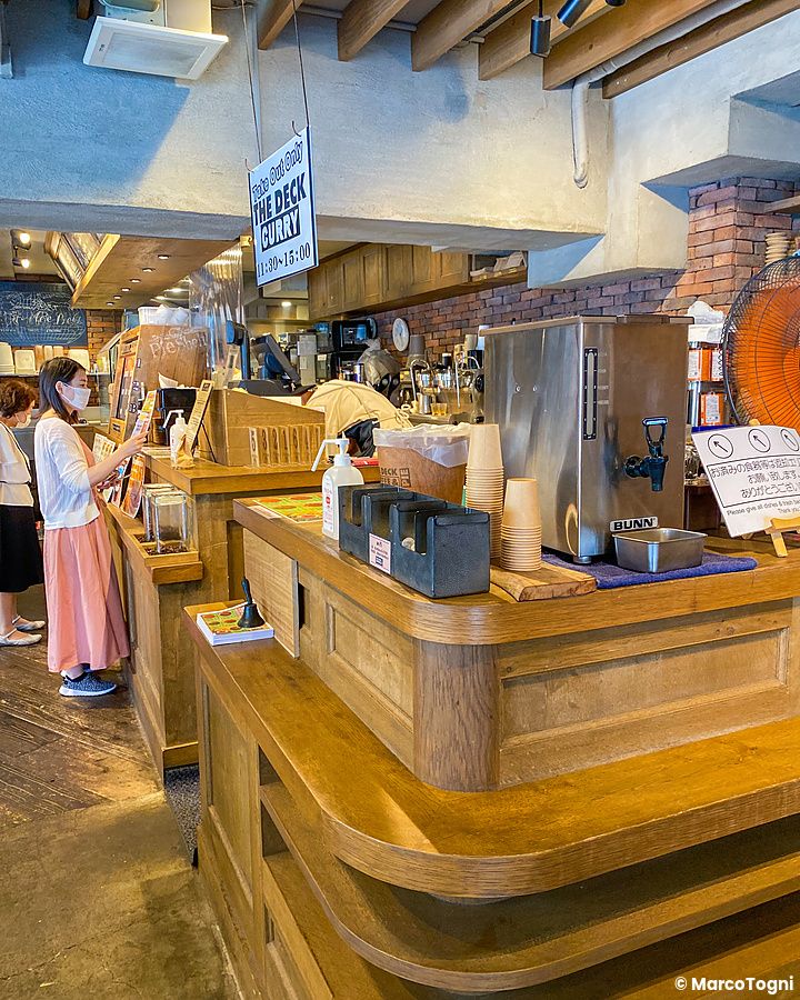 Interno del caffè The Deck Coffee & Pie a Tokyo con un bancone in legno e una persona in attesa al bancone.