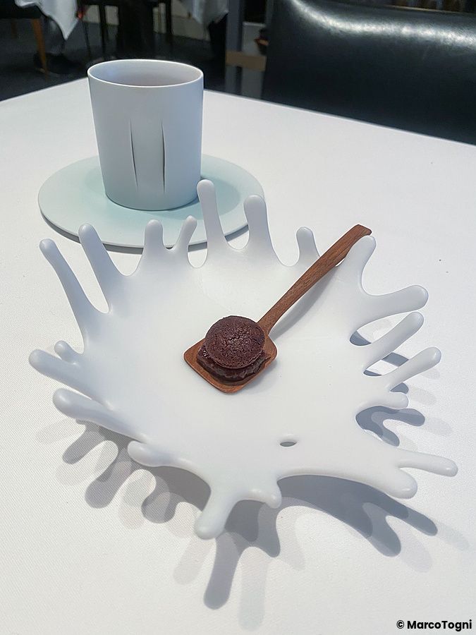 Un dolcetto con caffè servito su un cucchiaino di legno e un piatto bianco sagomato presso il ristorante Koji Shimomura.