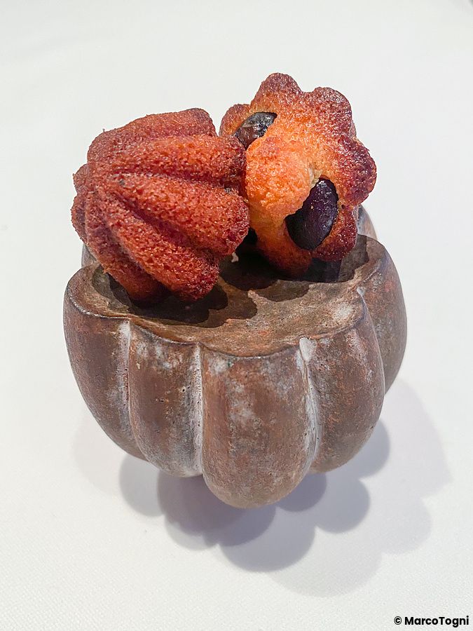 Un financier con olive servito all'interno del ristorante Edition Koji Shimomura su una piccola ciotola in ceramica.