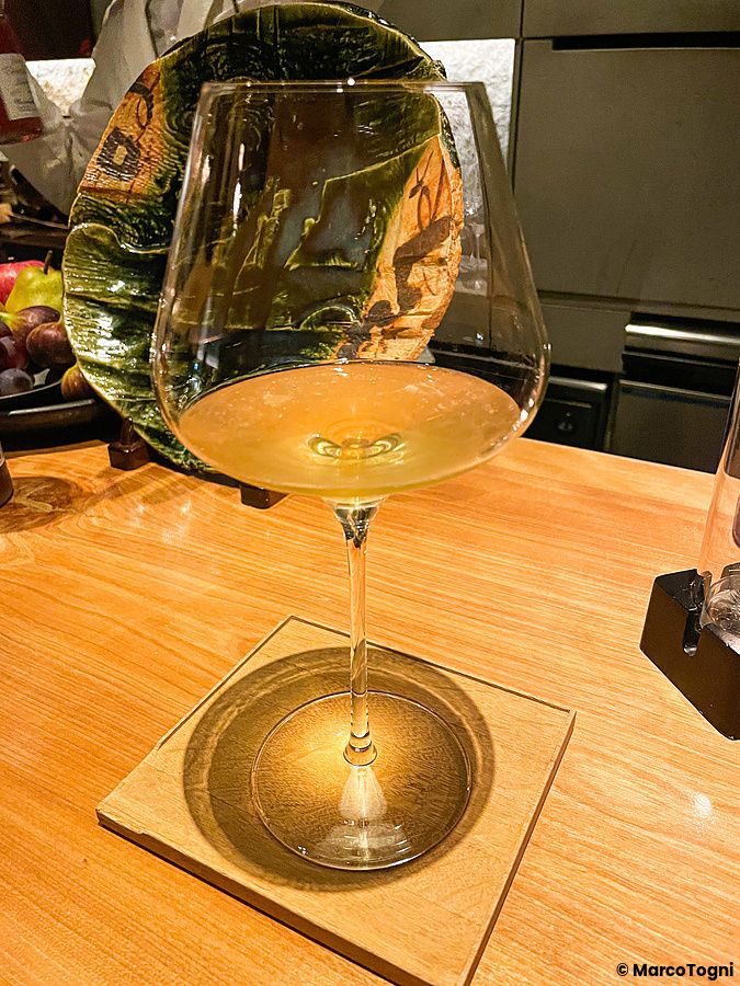 Un calice con cocktail dorato su sottobicchiere in legno al bancone del Mixology Salon a Ginza, Tokyo.