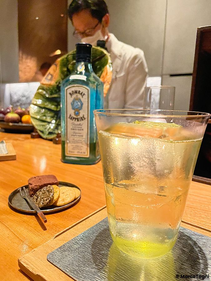 Un bicchiere di cocktail sul bancone del Mixology Salon a Ginza con una bottiglia di Bombay Sapphire sullo sfondo.