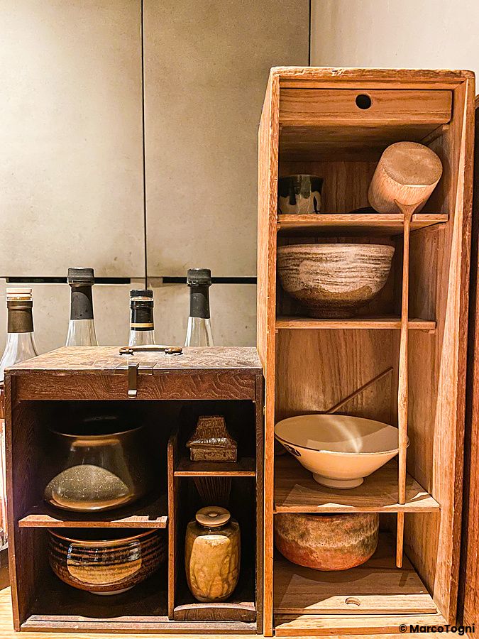 Scaffalature in legno con ciotole in ceramica e bottiglie di vetro all'interno del Mixology Salon di Ginza, Tokyo.